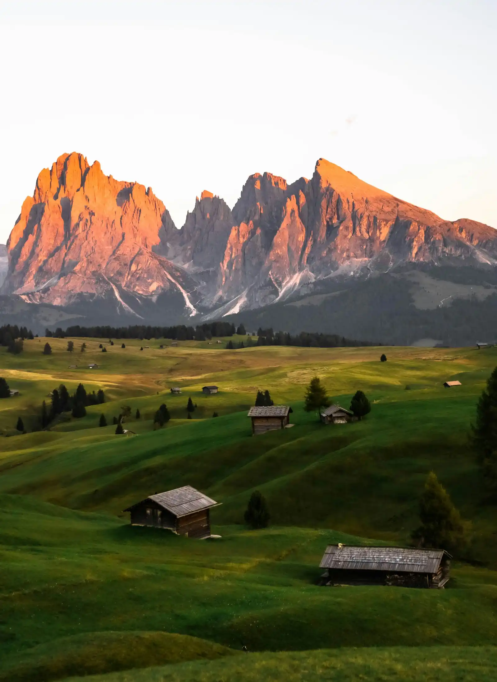 Best Time to Get Married in the Dolomites: A Season-by-Season Guide Alpe di Siusi meadow with wooden huts and the Sassolungo peaks lit by alpenglow