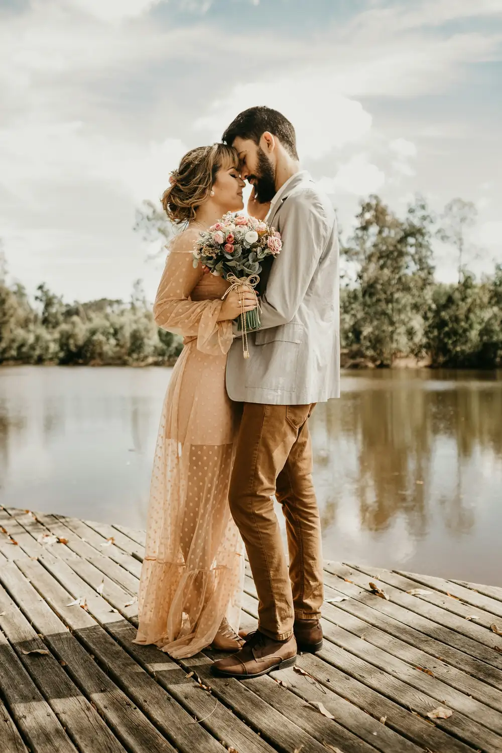 How Much Does a Destination Wedding or Elopement in the Dolomites Cost? Couple embracing on a wooden jetty beside a calm lake