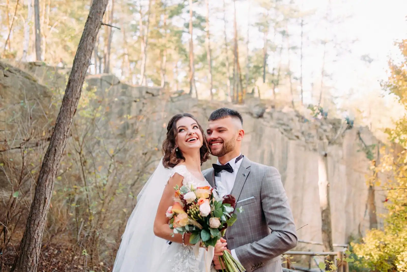 Legal Requirements for a Destination Wedding in Italy: What Foreign Couples Need to Know Smiling bride and groom with a bouquet beside a stone wall in an autumn forest